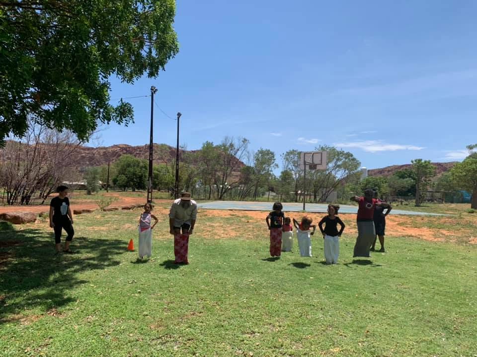 Children and adults taking part in a sack race on the community oval
